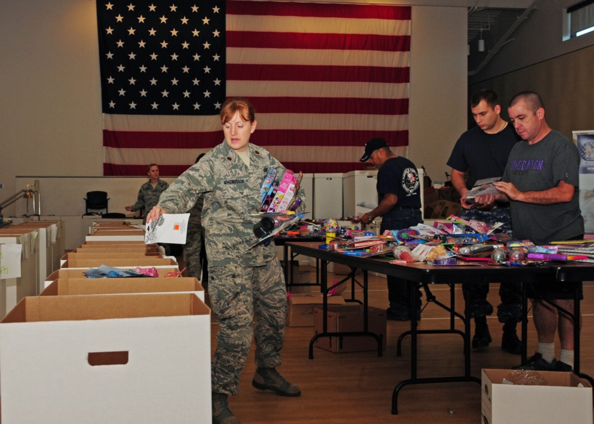 Maj. Elizabeth Magnusson, 944th Fighter Wing chief of public affairs, volunteers to distribute toys in the proper boxes Dec. 18 for Operation Holiday Open House at the Navy Operation Support Center at Luke Air Force Base, Ariz. (U.S. Air Force photo taken by Tech. Sgt. Louis Vega Jr.)