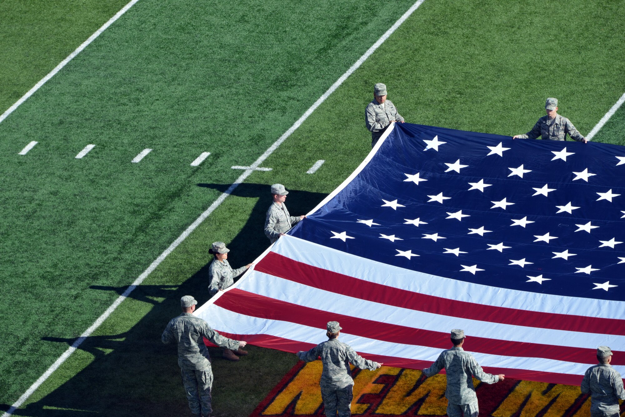 Kirtland Airman present a giant American flag during the national anthem at New Mexico Bowl Dec. 20. The game, in which Utah State University defeated the University of Texas-El Paso 21-6, took place at the University of New Mexico's Branch Field. (Photo by Damian Bohannon)