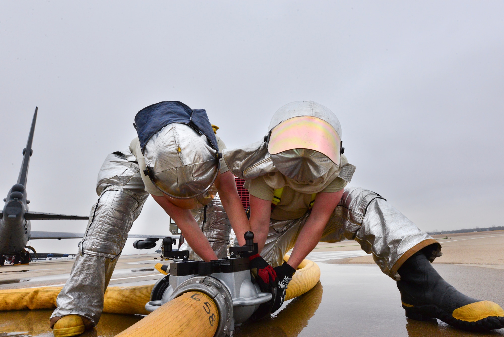Senior Airman Justin Smith (left) and Airman 1st Class Jordan Mahaney (right) work on a gated wye coupler during an aircrew egress exercise on Barksdale Air Force Base, La., Dec. 22, 2014. A gated wye is used to distribute water from one location to two separate locations. (U.S. Air Force photo/Airman 1st Class Mozer O. Da Cunha)