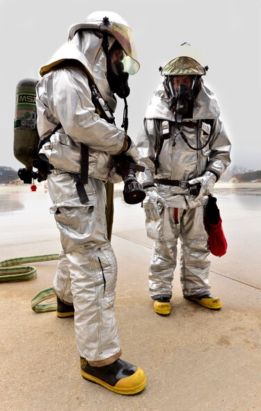 Airman 1st Class Devin Fawcett (left) and Staff Sgt. Isaac Holley (right), 2nd Civil Engineer Squadron firefighters, stand by to provide egress firefighters with a fire escape route during an aircrew egress exercise on Barksdale Air Force Base, La., Dec. 22, 2014. The fire proximity suit is used specifically for aircraft fires and protects the firefighter from thermal radiation and temperatures that can reach up to 2,000 degrees Fahrenheit. (U.S. Air Force photo/Airman 1st Class Mozer O. Da Cunha)