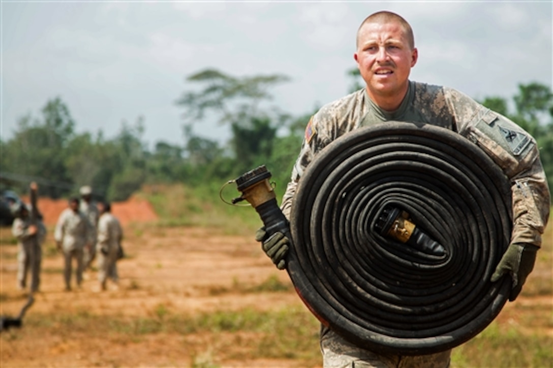 U.S. Army Spc. Dustin Atkins brings a set of fuel hose back to a CH-47 Chinook helicopter after fueling a UH-60 Black Hawk helicopter in Tapita, Liberia, Dec. 19, 2014. Atkins is a crew chief assigned to the 1st Armor Division's Company B, 2nd Battalion, 501st Aviation Regiment, from Fort Bliss, Texas.