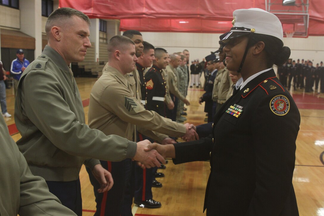 Gunnery Sgt. Jason MacLeod, staff noncommissioned officer-in-charge of Recruiting Substation Boston, congratulates a member of the Lynn English High School Junior Reserve Officers' Training Corps drill team, Lynn, Massachusetts, for her completion of a drill knock-out event during the JROTC drill competition at Quincy High School, Quincy, Mass., Dec. 20. RSS Boston is part of Recruiting Station Portsmouth, 1st Marine Corps District.