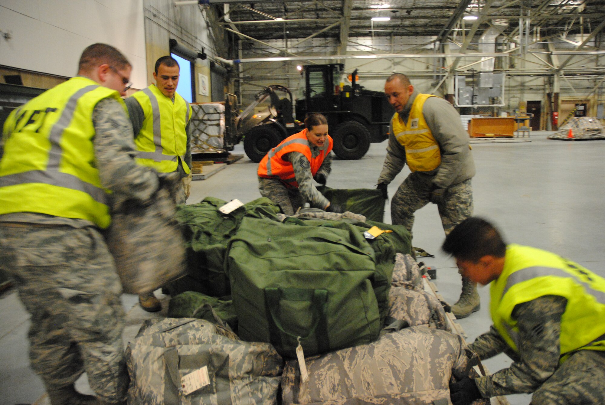 (Form left to right) Senior Airman Adam Kramer, Senior Airman Arturo Perez, Master Sgt. Tiffany Kuczkowski, Tech. Sgt. Alejandro Lopez and Senior Airman Mike Chiu, work as a team to prepare a cargo palette prior to being weighed and then loaded onto a pseudo cargo jet during a military deployment exercise on Grand Forks Air Force Base, N.D., Dec. 19, 2014. The team ensured the cargo of more than 80 passengers was properly organized during the exercise as quickly and as safely as possible.(U.S. Air Force photo/Staff Sgt. Luis Loza Gutierrez)