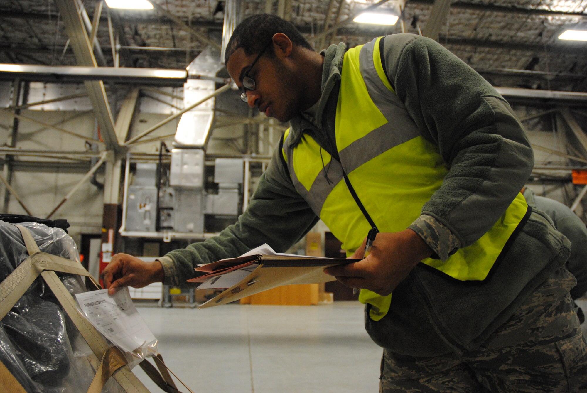 Airman 1st Class Hal Chambliss from the 319th Logistics Readiness Squadron verifies that the information on the cargo slip matches the quantities and types of equipment documented on his cargo list during a military deployment exercise on Grand Forks Air Force Base, N.D., Dec. 19, 2014. Chambliss role in the exercise was in-checker. (U.S. Air Force photo/Staff Sgt. Luis Loza Gutierrez)