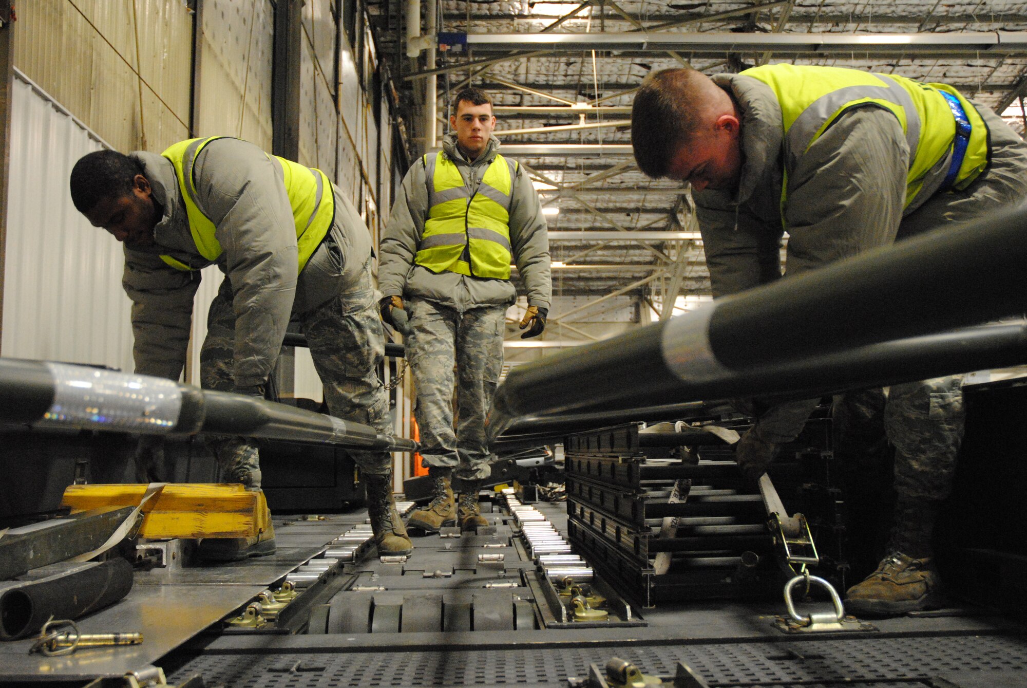 Airmen 1st Class Tyler Jones, Airmen 1st Class Randall Logan and   Senior Airman Cory Churchill perform a series of safety checks on a 25K loader being prepared to serve as the platform of a psuedo cargo jet during a military deployment exercise on Grand Forks Air Force Base, N.D., Dec. 19, 2014. The trio from the 319th Logistics Readiness Squadron was part of a five-member load team that prepared the heavy-duty cargo vehicle for the pretend deployment. (U.S. Air Force photo/Staff Sgt. Luis Loza Gutierrez)