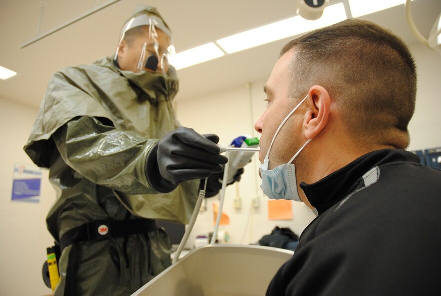 Wearing an In-Place Patient Decontamination Suit or biohazard suit, Dr. (Capt). Dongchul Paek, 319th MDOS flight surgeon, uses a thermometer to take Master Sgt. Brian Fair’s body temperature inside an isolation treatment room inside the Medical Treatment Facility on Grand Forks Air Force Base, N.D., Dec. 19, 2014. During a medical readiness exercise, Fair played the role of the Ebola patient, whose symptoms included fever, headache, abdominal pain and vomiting after returning from a trip to the African country of Liberia eight days prior to visiting the base clinic. (U.S. Air Force photo/Staff Sgt. Luis Loza Gutierrez)
