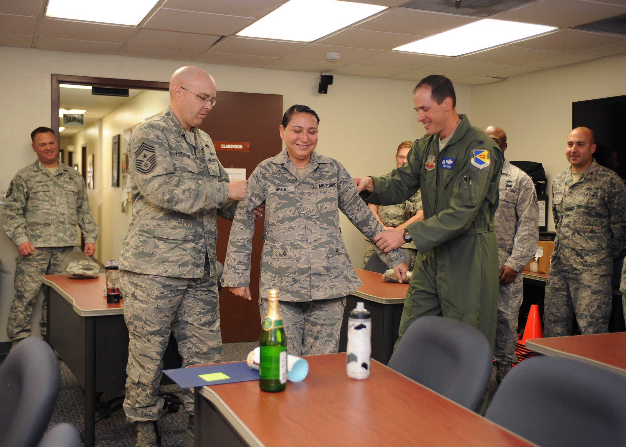 U.S. Air Force Col. James Meger, 355th Fighter Wing commander, and Chief Master Sgt. Ryan Peterson, 355th FW command chief, punch the rank of technical sergeant on to Tech. Sgt. Lisa Brow, 355th Civil Engineer Squadron NCO in charge of the Emergency Management flight’s training section, at Davis-Monthan Air Force Base, Ariz., Dec. 23, 2014. Brow was promoted via Stripes for Exceptional Performers for her consistent drive to serve her Airmen and excel in her career. (U.S. Air Force photo by Airman 1st Class Cheyenne Morigeau/Released) 