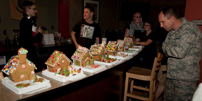 PETERSON AIR FORCE BASE, Colo. – Col. John Shaw, 21st Space Wing commander, as well as other wing leadership judge the completed gingerbread houses at the Chapel sponsored gingerbread house building contest at the Eclipse Café, Dec. 17, 2014. The contest was another event put on for Airmen to get together and have a good time. All supplies were provided by the Chapel, however many contestants brought extra supplies to support their creativity. (U.S. Air Force photo by Airman 1st Class Rose Gudex)
