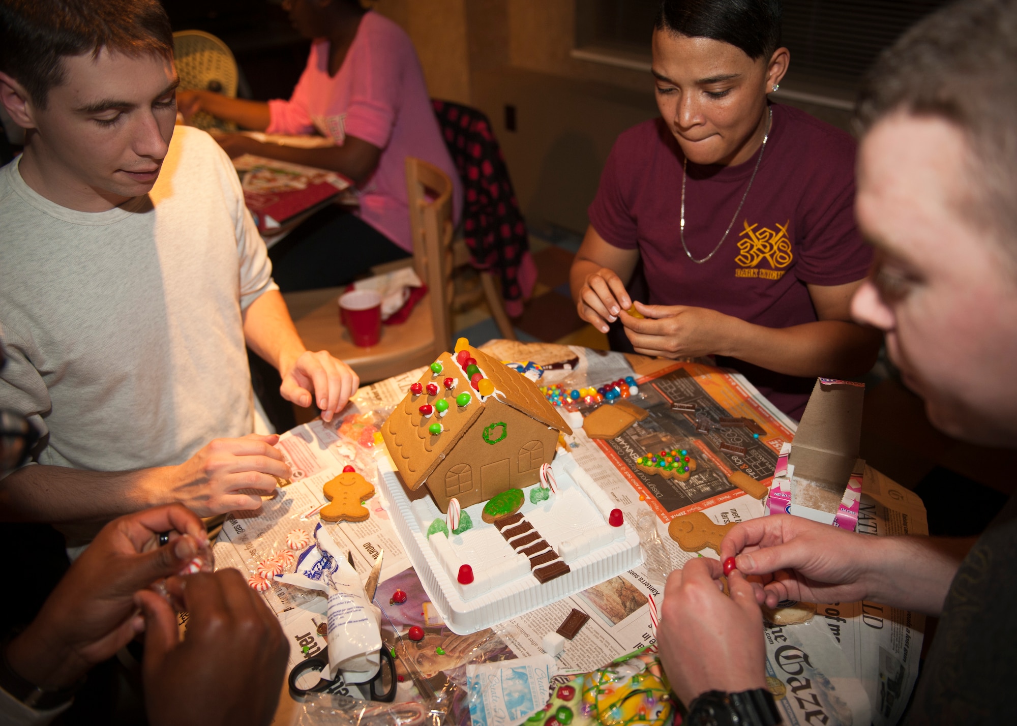 PETERSON AIR FORCE BASE, Colo. – A team of 21st Communications Squadron cyber transport operation technicians work as a team to put together their gingerbread house for the Chapel sponsored gingerbread house building contest at the Eclipse Café, Dec. 17, 2014. The contest was another event put on by the Chapel for Airmen to get together and have a good time. (U.S. Air Force photo by Airman 1st Class Rose Gudex)
