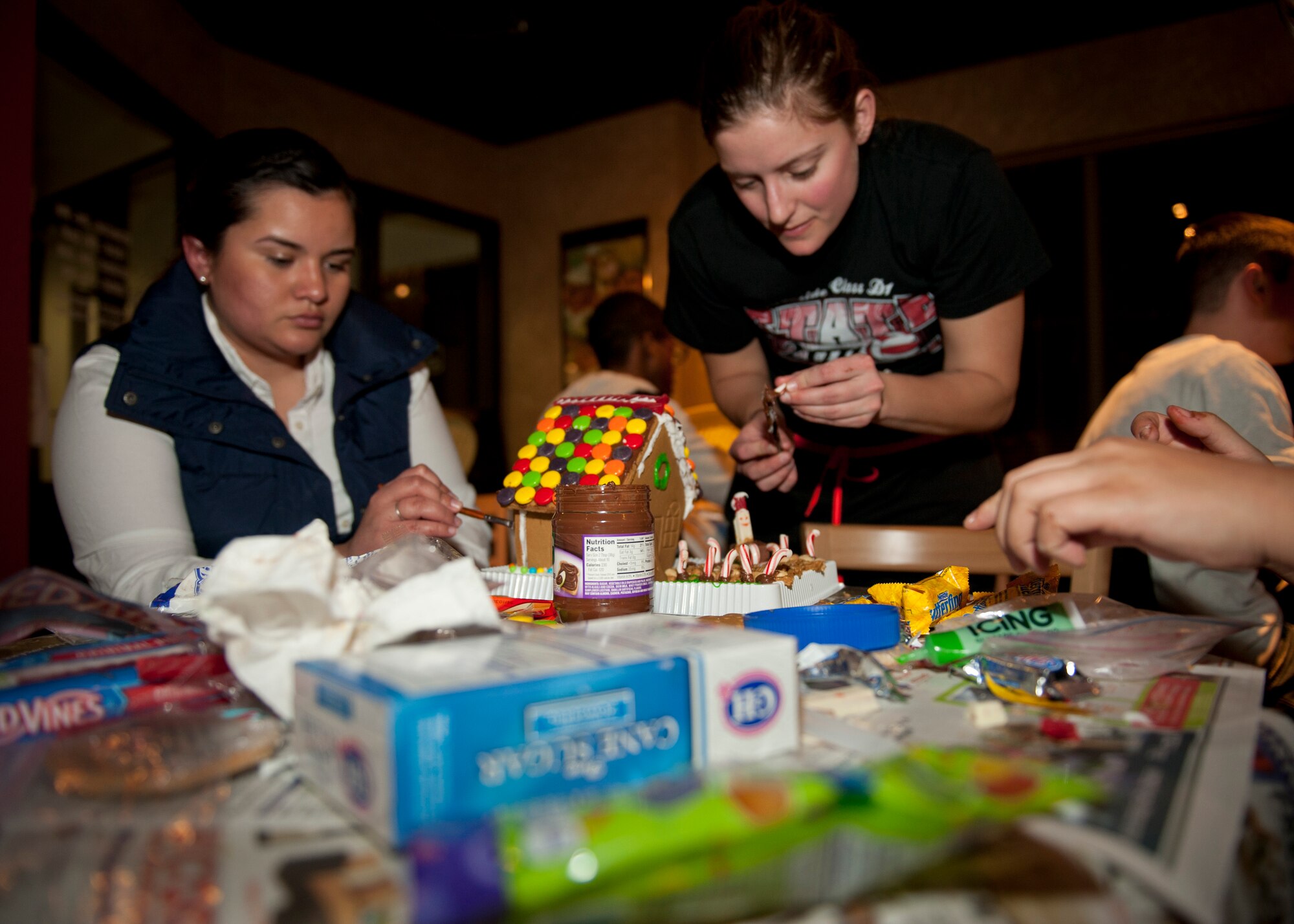 PETERSON AIR FORCE BASE, Colo. –Airmen 1st Class Andrea Canas (left) and Bridget Gray, 21st Dental Squadron dental technicians, compete in the chaos of the gingerbread house building contest sponsored by the Chapel at the Eclipse Café, Dec. 17, 2014. The contest was another event put on for Airmen to get together and have a good time. All supplies were provided by the Chapel. (U.S. Air Force photo by Airman 1st Class Rose Gudex)