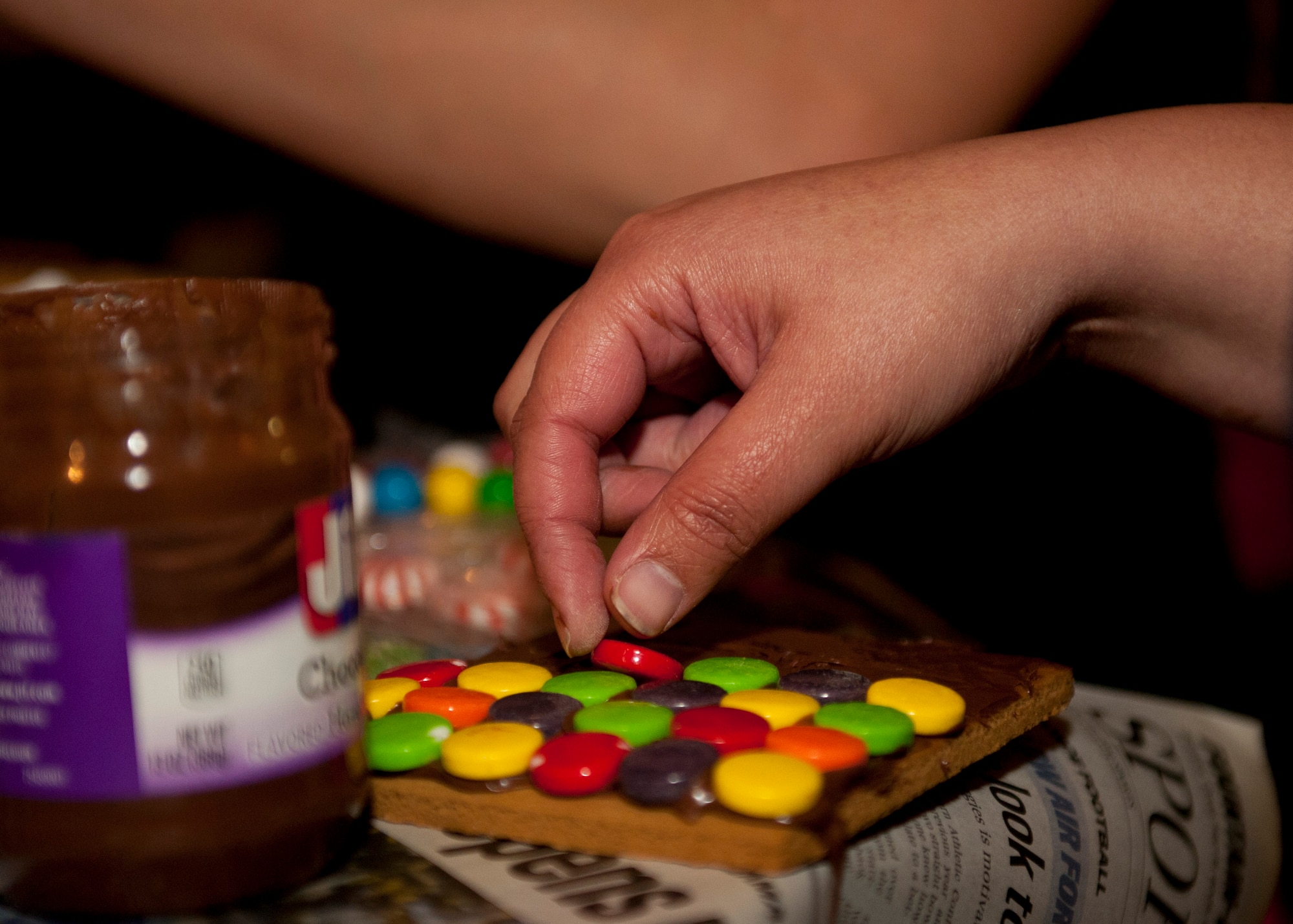 PETERSON AIR FORCE BASE, Colo. – Airman 1st Class Andrea Canas, 21st Dental Squadron dental technician, places candies on the roof of her team’s gingerbread house using a chocolate hazelnut spread at the Eclipse Café, Dec. 17, 2014. The gingerbread house building contest was another event the Chapel put on for Airmen to get together and have a good time. All the supplies, including food, drinks, gingerbread house supplies and prizes were all provided by the Chapel. (U.S. Air Force photo by Airman 1st Class Rose Gudex)
