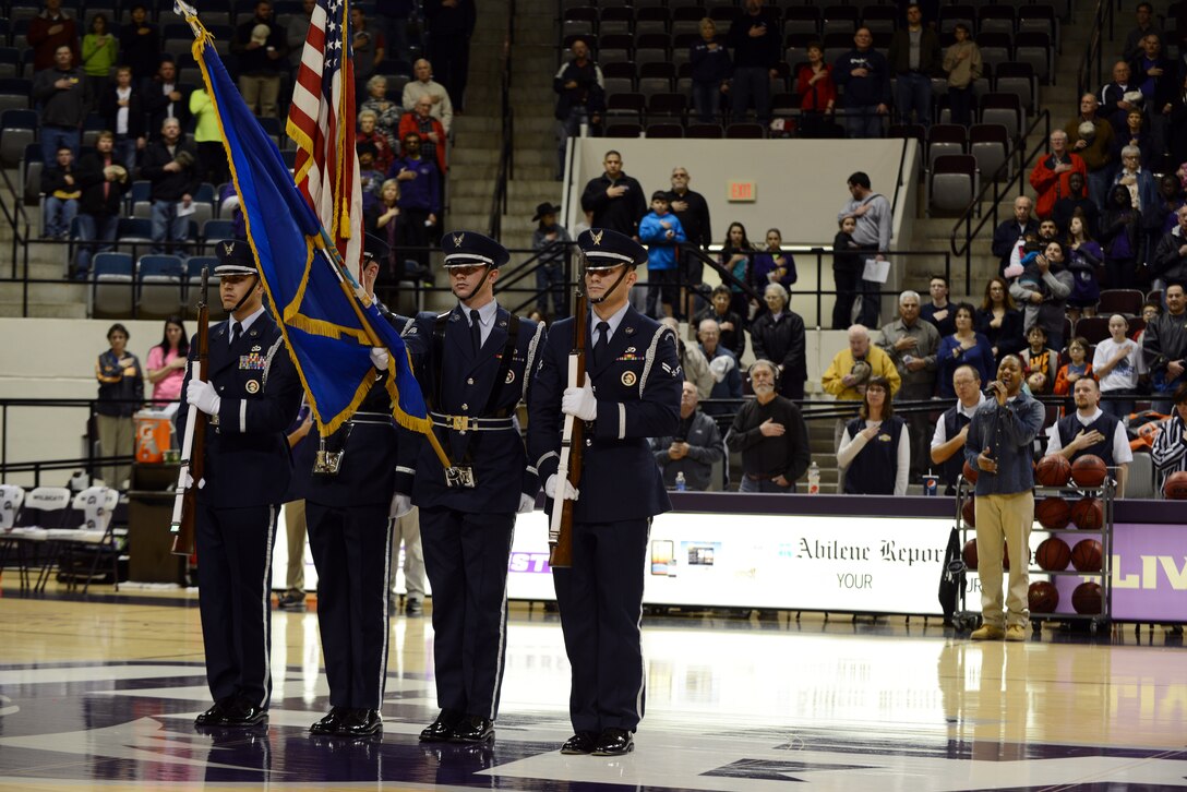 The Dyess Honor Guard presents the colors as U.S. Air Force Tech. Sgt. Derek Speights, 7th Component Maintenance Squadron, sings the National Anthem Dec. 20, 2014, at Moody Coliseum in Abilene, Texas.  ACU welcomed members of Team Dyess to the game free of admission for the free game as a part of the school’s Dyess Air Force Base Day.(U.S. Air Force photo by Airman 1st Class Kedesha Pennant/Released)