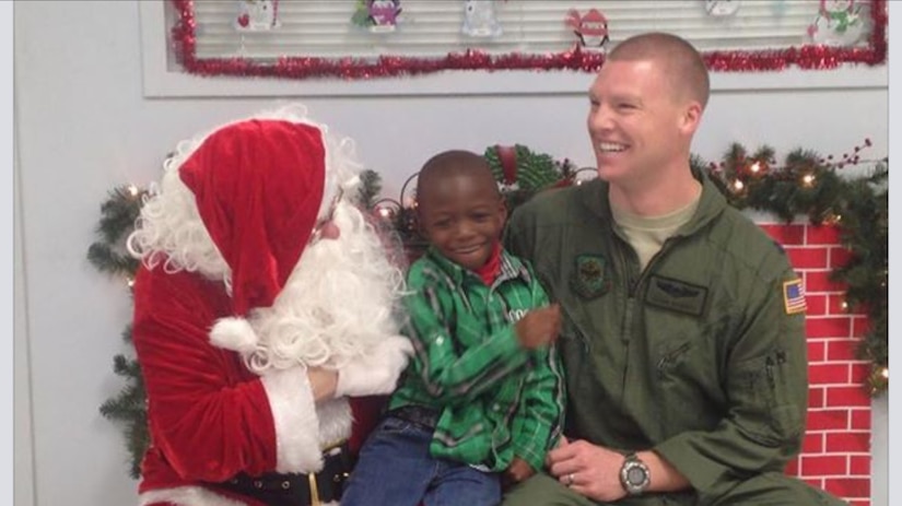 Capt. Jason Gossett, 15th Airlift Squadron C-17 Globemaster III pilot, and Santa Claus, sit with a student from Lambs Elementary School, Dec. 20, 2014, during the initial “Shop with Airman” program. The purpose of the event was to give deserving children an opportunity to go holiday shopping as well as provide a positive interaction with military members from Joint Base Charleston, S.C. (Courtesy Photo) 