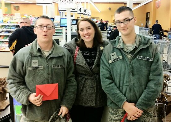 Senior Airman Matthew Frank, 22nd Logistics Readiness Squadron individual protective equipment journeyman, and Airman First Class Brett Simmons, 22nd LRS material management apprentice, pose for a photo with Amanda Chastain, McConnell Enlisted Spouse Club vice president, after receiving $50 gift cards at the base commissary during Operation Holiday Surprise, on McConnell Air Force Base, Kan., Dec 19th. The MESC donated 200 gift cards to random Airmen, ranked E-5 and below, during the 2014 holiday season. (Courtesy Photo)