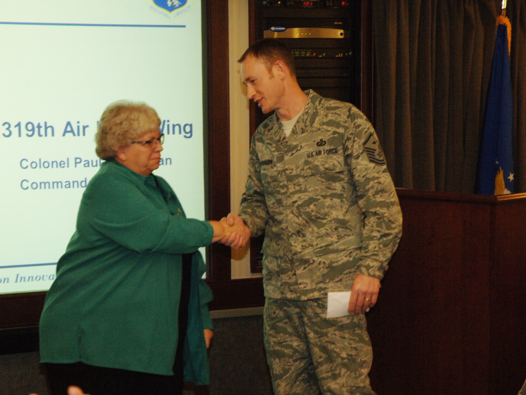 American Legion Auxiliary Vice President Diane Kraemer shaking hands with MSgt Keelan Rasmusson after presenting a $100 check that will go to the non-profit organization Operation Warmheart. The organization distrbutes charitable donations to service members and their families all year long especially during the holiday season.(U.S. Air Force photo/2nd Lt. James Fisher).
