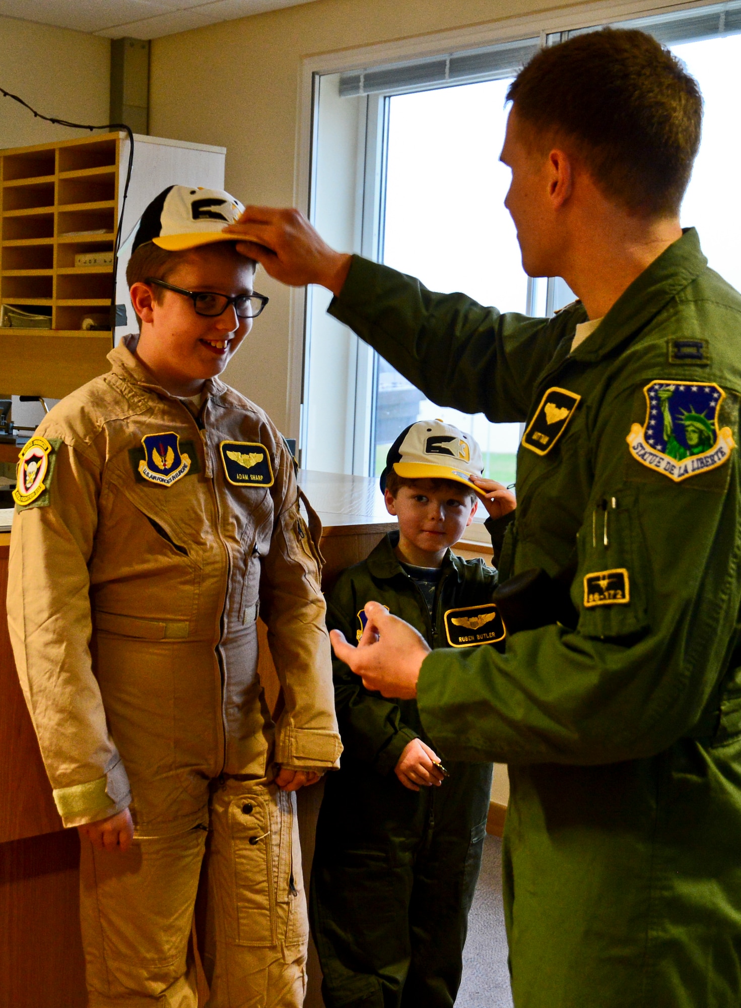 Capt. Matthew Tanis, 493rd Fighter Squadron F-15C Eagle pilot, presents hats to Adam Sharp and Ruben Butler as tokens to remember their day as “Pilots for a Day” at Royal Air Force Lakenheath, England, Dec. 22, 2014. "Pilot for a Day" was started at RAF Lakenheath in March 2012 by Maj. Jason Bianchi, 493rd Fighter Squadron pilot, with the intent to support children throughout local communities, fighting life-threatening illnesses or conditions, by providing a day of fun and a break from routine doctor and hospital visits. (U.S. Air Force photo by Airman 1st Class Erin R. Babis/Released)