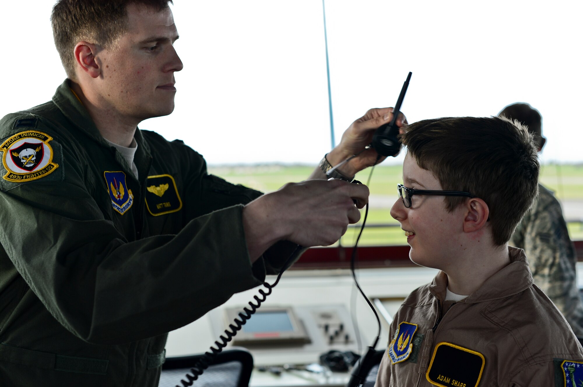 Capt. Matthew Tanis, 493rd Fighter Squadron F-15C Eagle pilot, fits a headset on Adam Sharp so he can communicate with a pilot out on the flightline during the “Pilot for a Day” event at Royal Air Force Lakenheath, England, Dec. 22, 2014. "Pilot for a Day" was started at RAF Lakenheath in March 2012 by Maj. Jason Bianchi, 493rd Fighter Squadron pilot, with the intent to support children throughout local communities, fighting life-threatening illnesses or conditions, by providing a day of fun and a break from routine doctor and hospital visits. (U.S. Air Force photo by Airman 1st Class Erin R. Babis/Released)