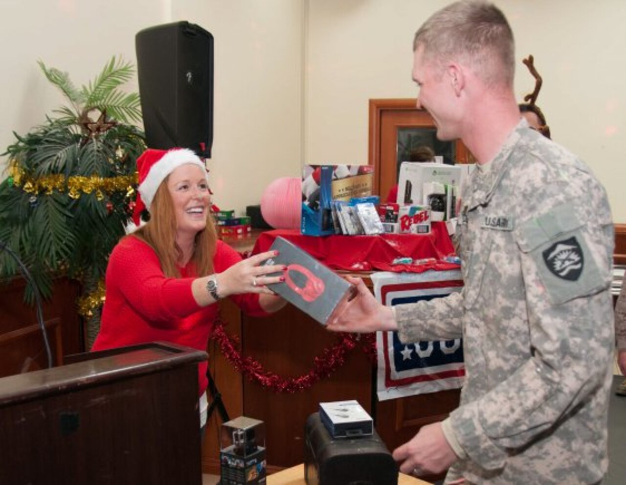 Priya Butler, director of operations, USO Southwest Asia, hands a set of Beats by Dre headphones to a soldier who won a raffle during a Christmas celebration in Baghdad, Iraq, Dec. 21, 2014. The 1st Infantry Division, the United States Department of State, the United Service Organizations, the New York Yankees and many other organizations, gathered more than 7,000 presents to show their support for Service members in Iraq.