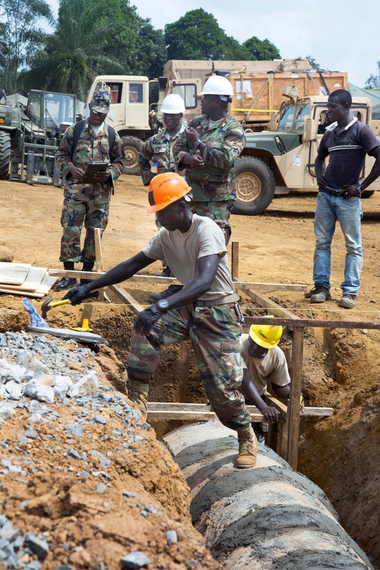 Engineers with the armed forces of Liberia install a drainage culvert at a new Ebola treatment unit being built in support of Operation United Assistance in Gbediah, Liberia, Dec. 19, 2014.
