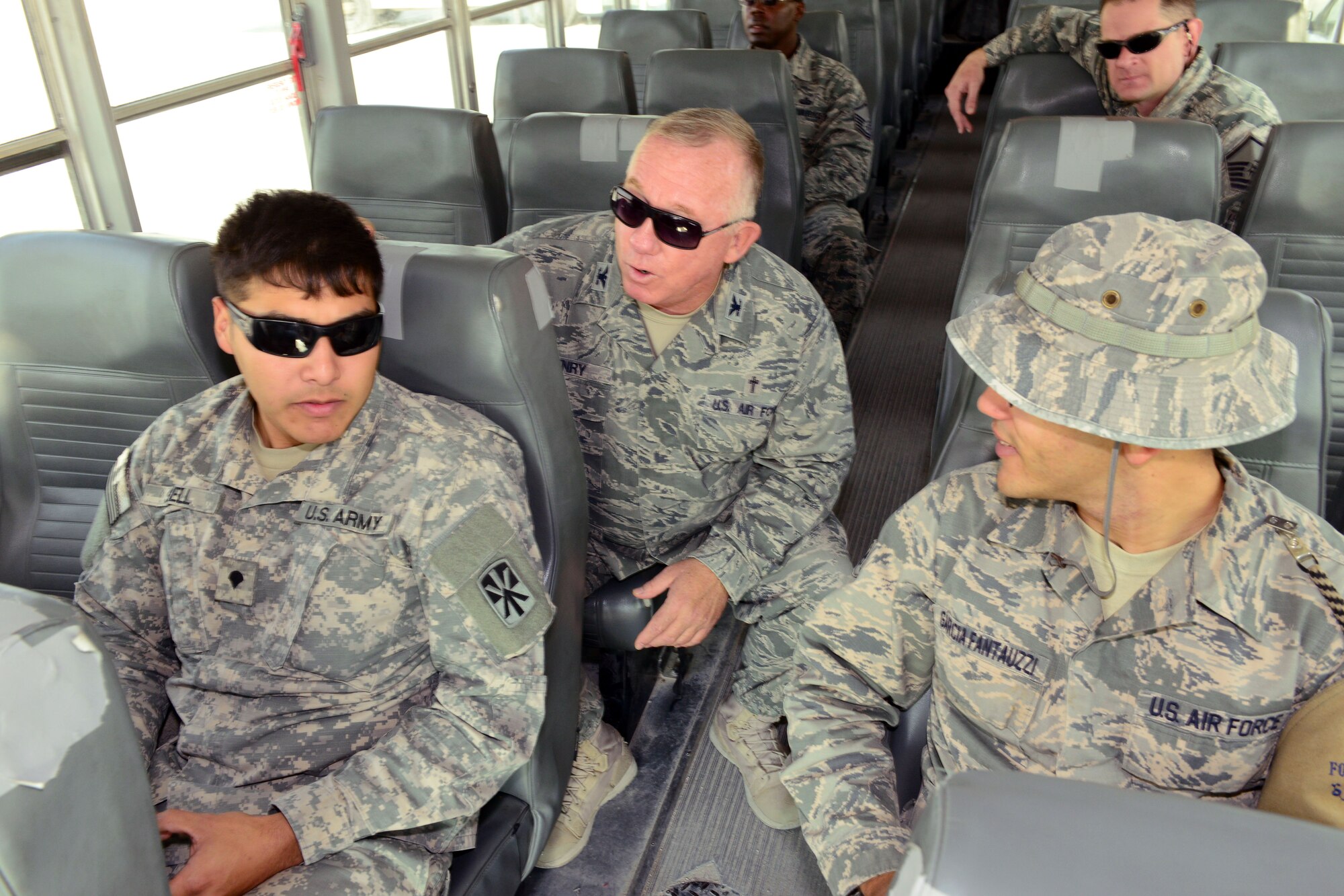 U.S. Air Force Col. Gerald Henry, 379th Air Expeditionary Wing chaplain (left), makes his rounds on the base shuttle, December 23, 2014, during his visit with U.S. servicemembers deployed to Al Udeid Air Base, Qatar, as part of Operation Build Up Spirituality. The operation is an all-out effort by the Al Udeid chapel team, first sergeants and military and family life counselors to increase resiliency for U.S. servicemembers deployed far away from home and from loved ones during the holiday season. (U.S. Air Force photo by Master Sgt. Kerry Jackson)