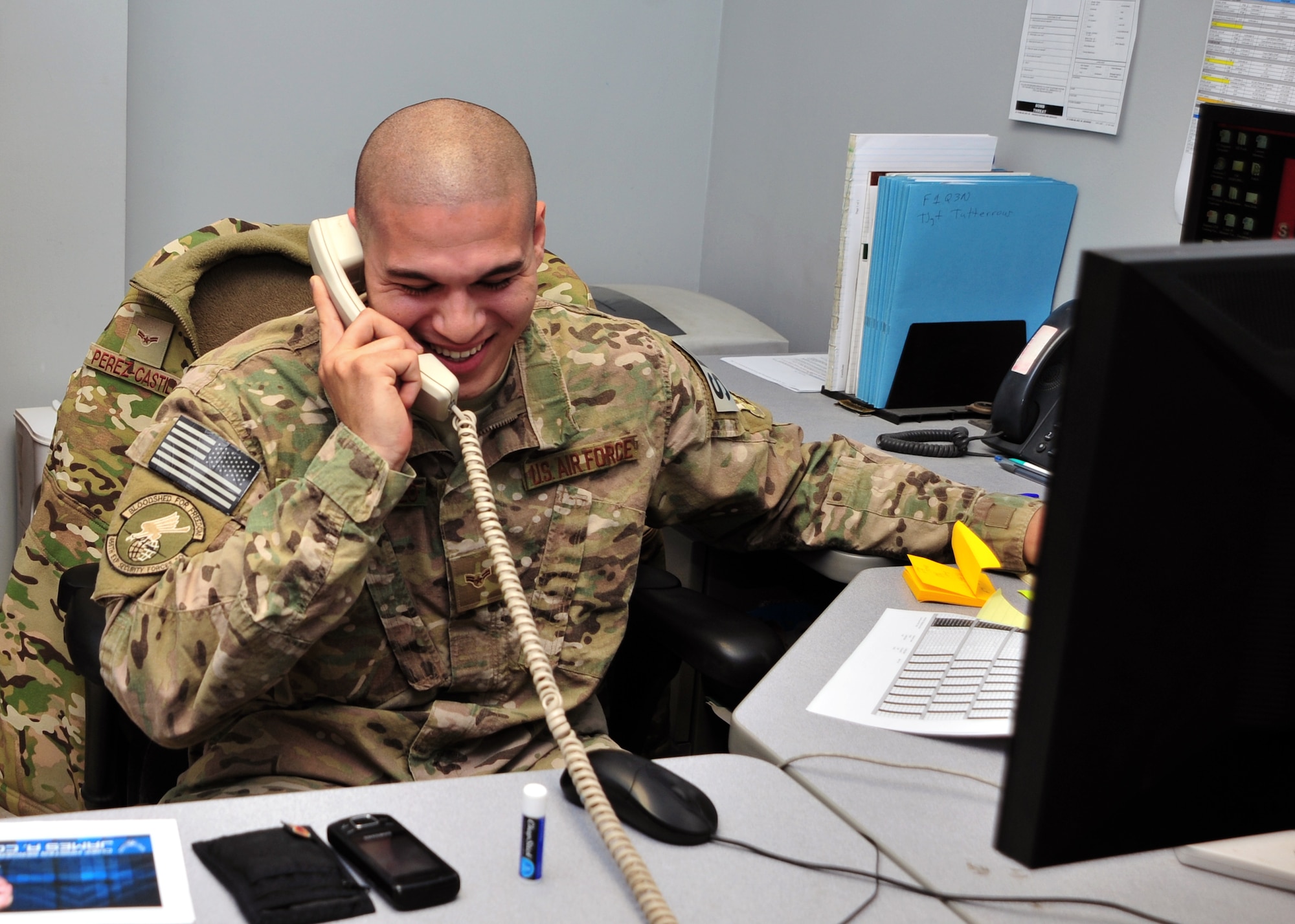 U.S. Air Force Airman 1st Class Frank Perez-Castillo, 455th Expeditionary Security Forces Squadron Commander Support Staff, smiles during a surprise phone call from Chief Master Sgt. of the Air Force James A. Cody Dec. 24, 2014 at Bagram Airfield, Afghanistan. During the call, Cody expressed his well-wishes for the coming year and communicated his gratitude for Castillo-Perez’s service. (U.S. Air Force photo by Staff Sgt. Whitney Amstutz/released)
