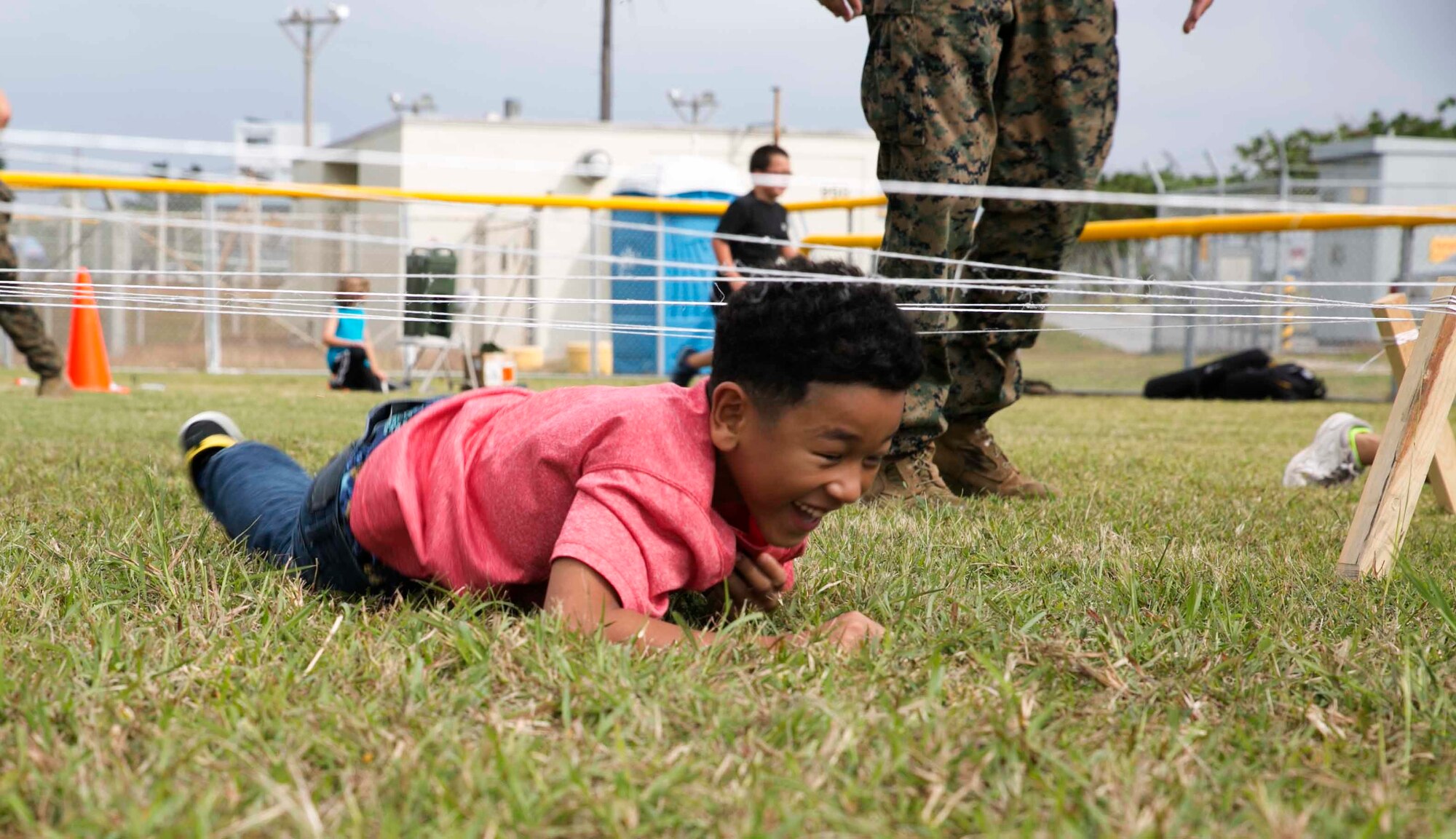 Anthony Louis, a student at Kinser Elementary School, crawls under string that simulates barbed wire Dec. 10 during a Warrior Day on Camp Kinser. “The purpose of Warrior Day is to provide the children of Kinser Elementary School an opportunity to conduct training similar to what their parents do,” said Staff Sgt. Tracie Mahan, a machinist with 3rd Maintenance Battalion, Combat Logistics Regiment 35, 3rd Marine Logistics Group, III Marine Expeditionary Force. 