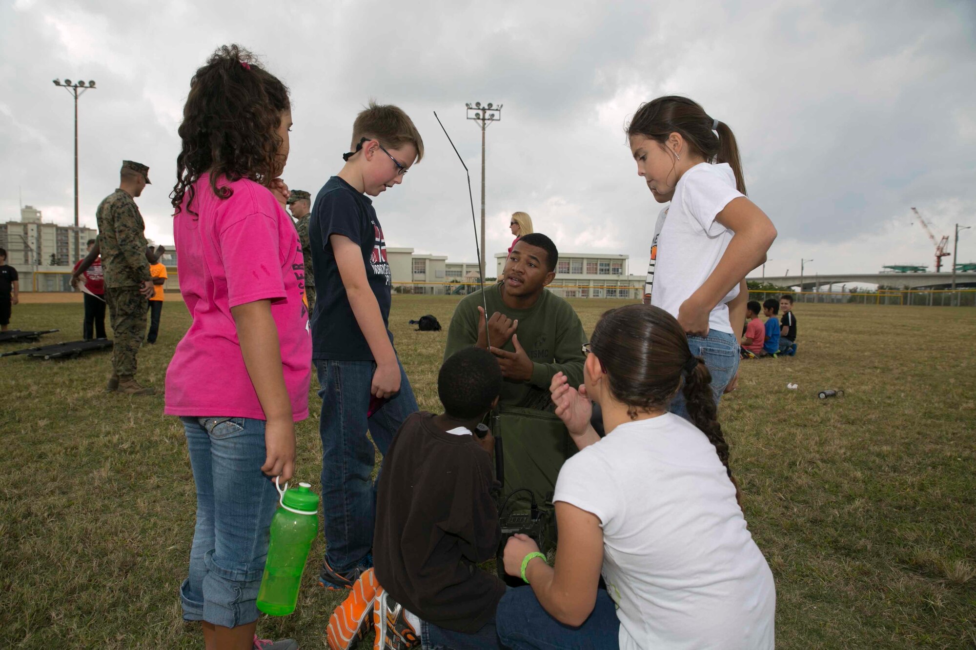 Cpl. Xavier L. Melton, from Birmingham, Alabama, teaches 4th grade students from Kinser Elementary School how to use an AN/PRC-119F radio Dec. 10 during Warrior Day on Camp Kinser. Warrior Day teaches service members’ children more about what their parents do in the military on a regular basis. Xavier is a field radio operator with Headquarters Regiment, 3rd Marine Logistics Group, III Marine Expeditionary Force. 