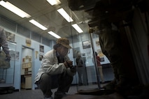 Tomimori Asato takes video footage of combat attire that American service members wore in the Battle of Okinawa during a tour of the Camp Kinser Battle of Okinawa Historical Exhibit Dec. 18. Twenty-four local museum curators and employees visited the exhibit after they were surveyed by the U.S. Consulate General Naha and expressed interest in the exhibit. One of the consulate’s goals is to strengthen ties with the historical and cultural institutions on Okinawa, according to Dolores Prin, public affairs officer with the consulate.