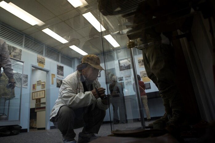 Tomimori Asato takes video footage of combat attire that American service members wore in the Battle of Okinawa during a tour of the Camp Kinser Battle of Okinawa Historical Exhibit Dec. 18. Twenty-four local museum curators and employees visited the exhibit after they were surveyed by the U.S. Consulate General Naha and expressed interest in the exhibit. One of the consulate’s goals is to strengthen ties with the historical and cultural institutions on Okinawa, according to Dolores Prin, public affairs officer with the consulate.