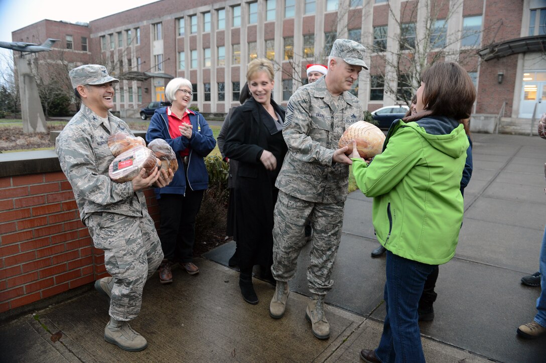 Col. David Kumashiro (left), 62nd Airlift Wing commander, and Chief Master Sgt. Gordon Drake, 62nd Airlift Wing command chief, receive hams from local community leaders Dec. 18, 2014, during Operation Ham Grenade at Joint Base Lewis-McChord, Wash. The hams donated from local community leaders will be given to Airmen for their upcoming holiday meal. (U.S. Air Force photo/Airman 1st Class Keoni Chavarria)