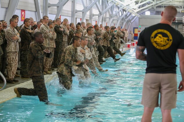 Recruits of Bravo Company, 1st Recruit Training Battalion, step into the water to perform a 25-meter swim across the shallow end of the pool during the Water Survival Basic Qualification at Marine Corps Recruit Depot San Diego, Dec. 15.  Recruits are required to wear the Marine Corps Camouflaged Utilities Uniform and combat boots.  The extra items weigh down the recruits, restricting swim movements they may be used to. 