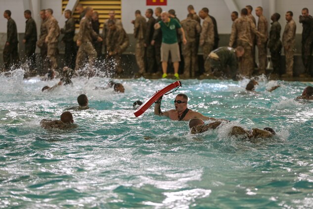 A Marine Corps Instructor of Water Survival monitors recruits of Bravo Company, 1st Recruit Training Battalion, as they perform a 25-meter swim across the shallow end of the pool during the Water Survival Basic Qualification at Marine Corps Recruit Depot San Diego, Dec. 15.  Instructors watch to make sure recruits did not touch the bottom of the pool during the swim, which would result in a failure.