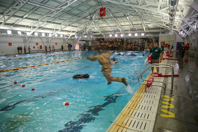 Recruits of Bravo Company, 1st Recruit Training Battalion, jump to their pack and perform a 25-meter swim using a waterproof pack during the Water Survival Basic Qualification at Marine Corps Recruit Depot San Diego, Dec. 15.  The swim qualification introduces new challenges that recruits must overcome in order to graduate recruit training.