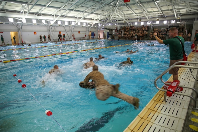 Recruits of Bravo Company, 1st Recruit Training Battalion, jump to their pack and perform a 25-meter swim using a waterproof pack during the Water Survival Basic Qualification at Marine Corps Recruit Depot San Diego, Dec. 15.  The swim qualification introduces new challenges that recruits must overcome in order to graduate recruit training.