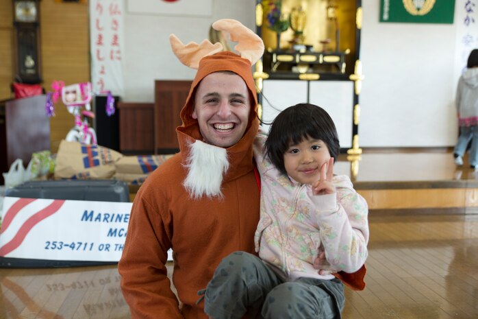 A volunteer from Marine Corps Air Station Iwakuni, Japan, poses with a child during a visit to a children’s home in Houfu, Japan, Dec. 23, 2014. The Marine Thrift Store hosted the visit after collecting toys during a toy drive and motorcycle rally earlier this year. The rally collected more than 300 toys to give to the children’s home. 