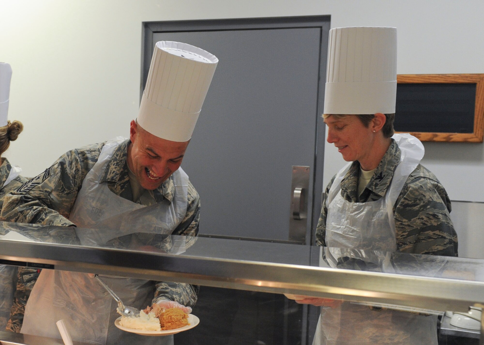 WRIGHT-PATTERSON AIR FORCE BASE, Ohio – Col. Leah Lauderbach, National Air and Space Intelligence Center commander, and Chief Master Sgt. Troy Eden, NASIC command chief serves dinner at the Pitsenbarger Dining Facility, here Dec. 18. Each year the dining facility staff prepares a special Christmas themed dinner for patrons. Throughout the evening several Wright-Patterson senior leaders served the dinner to Airmen as a gesture of appreciation for their hard work. (U.S. Air Force photo/Airmen 1st Class Samuel Earick)