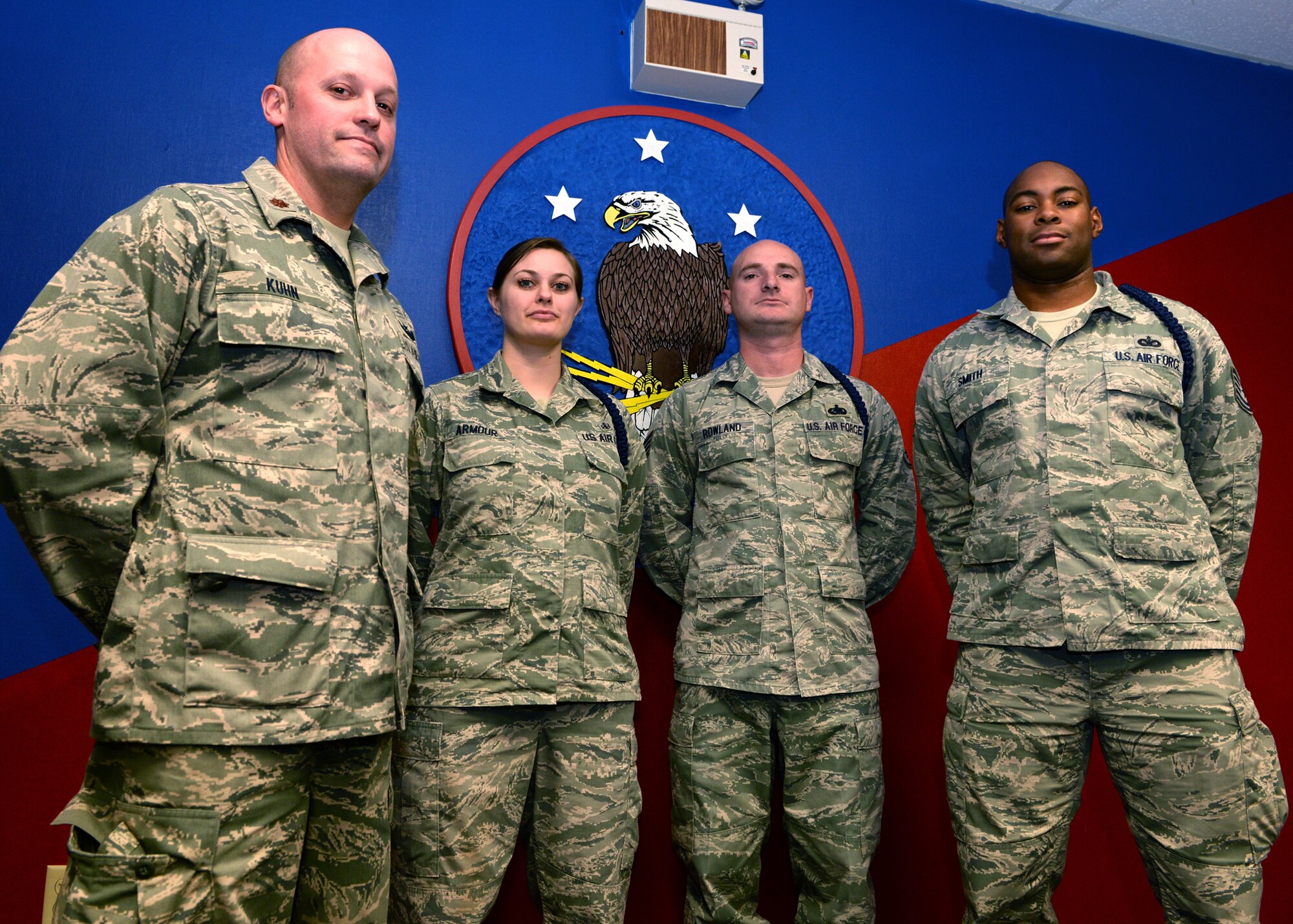 ALTUS AIR FORCE BASE, Okla. – U.S. Air Force Maj. Greg Kuhn, 97th Training Squadron military training flight commander, U.S. Air Force Staff Sgts. Martina Armour and Timothy Rowland, and U.S. Air Force Tech. Sgt. Mark Smith, 97th Training Squadron military training leaders, stand in front of the 97th TRS patch, Dec. 10, 2014. As loadmaster and boom operator students enter their technical training at Altus Air Force Base, they rely on this small group of military training leaders to help with issues and uphold military standards. (U.S. Air Force photo by Airman 1st Class Nathan Clark/Released)