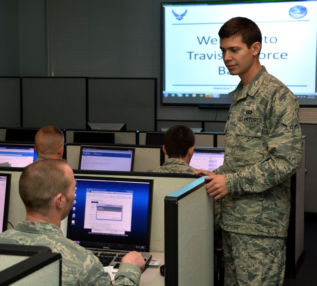 Air Force Airman Dimas Bernacchia assists an in-processing service member with a travel voucher at Travis Air Force Base, Calif., Dec. 10, 2014. Bernacchia holds dual citizenship in the United States and Italy. U.S. Air Force photo by Senior Airman Charles Rivezzo