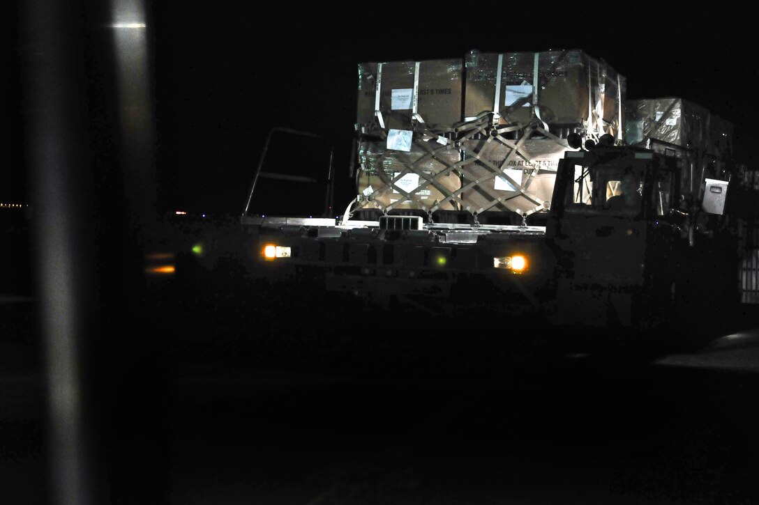 A U.S. Air Force aircraft cargo loading and unloading vehicle, carrying four tons of holiday mail, approaches the tail end of a C-130 Hercules cargo plane on Ali Al Salem Air Base in Kuwait, Dec. 23, 2014.