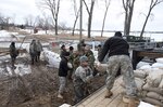 Soldiers from the South Dakota Army National Guard's Forward Support Company, 153rd Engineer Battalion, Huron, and the 200th Engineer Company, Pierre, Detachment 1 -Chamberlain and Detachment 2 - Mobridge, work together in the effort against the flood by sandbagging around the sewage lift station, located near Waubay, S.D., March 25, 2010.