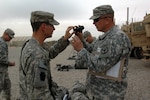 Spc. Jonathan Piccone, an infantryman with F troop, 2nd Squadron, 278th Armored Cavalry Regiment of the Tennessee National Guard, hands his night vision sight to Sgt. William Rhinehart, a team leader with F troop, during pre-mission checks and inspections prior to a convoy-logistics patrol at Joint Base Balad, Iraq March 24, 2010. Leaders at every level conduct multiple checks and inspections prior to missions in order to ensure success.