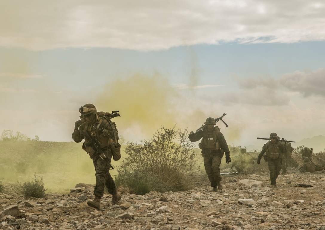 U.S. Marines with Battalion Landing Team 3rd Battalion Team, 1st Marine Regiment, 15th Marine Expeditionary Unit, move under the concealment of smoke during a combined arms exercise aboard Marine Corps Air Ground Combat Center, Twentynine Palms, Calif., Dec. 15, 2014. BLT 3/1 conducted this training concurrent with the 15th MEU’s realistic urban training.  RUT prepares the 15th MEU’s Marines for their upcoming deployment, enhancing their combat skills in environments similar to those they may find in future missions. (U.S. Marine Corps Photo by Sgt. Emmanuel Ramos/Released)