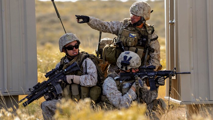 U.S. Marine Capt. Erich Lloyd, 1st Air Naval Gunfire Liaison Company forward air controller deployed from Camp Pendleton, Calif., directs team movements during an exercise urban combat scenario during exercise Mountain Roundup 2013 at Juniper Butte Range, about 70 miles from Mountain Home Air Force Base, Idaho, Oct. 8, 2013. Lloyd, a prior-enlisted crew chief, used U.S. Navy AV-8B Harriers and Republic of Singapore Air Force F-15SG Strike Eagles air assets to neutralize enemy forces.
