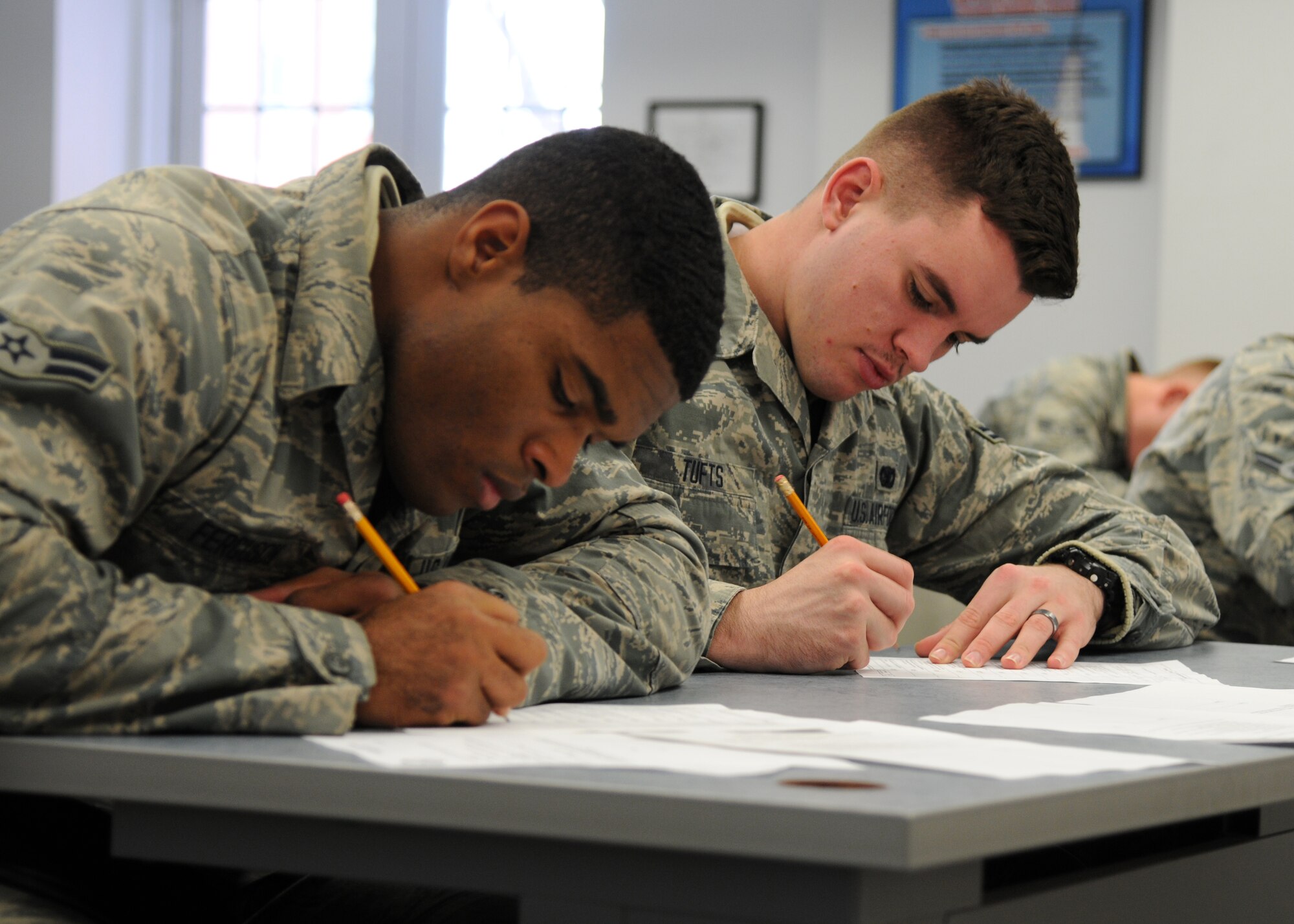 Airmen 1st Class Akeem Ferguson and Kevin Tufts fill out paperwork during their Unit Orientation Training Dec. 22, 2014, on F.E. Warren Air Force Base, Wyo. During the training, security forces members learn the basic skills they need to accomplish the mission.  Ferguson and Tufts are with the 90th Missile Security Forces Squadron. (U.S. Air Force photo/Airman 1st Class Malcolm Mayfield)
