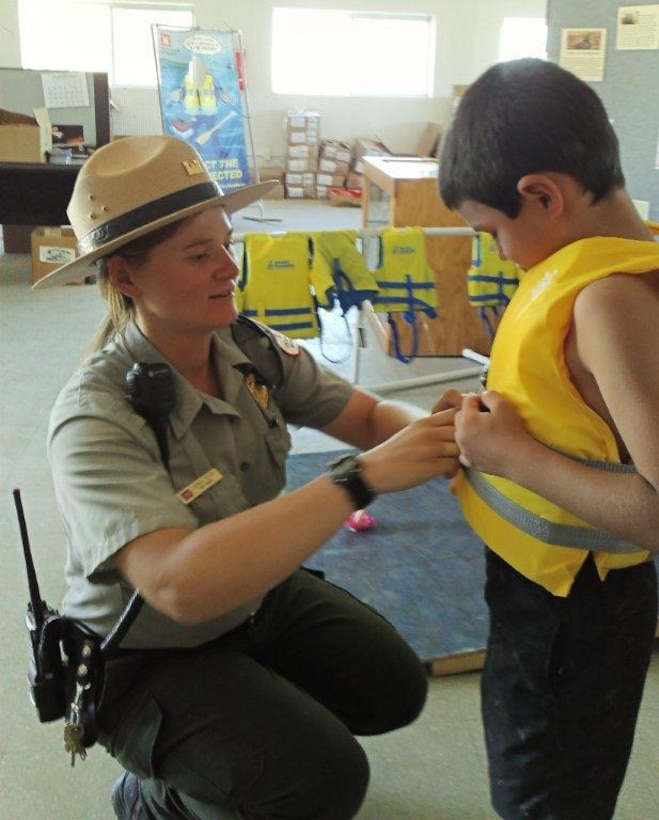 2014 District Photo Drive entry. Photo by Valerie Mavis, Aug. 31, 2014.  “Conchas Seasonal Park Ranger Lauren Boyer assists a young visitor with the proper fitting and wear of a U.S. Coast Guard-approved life jacket.”