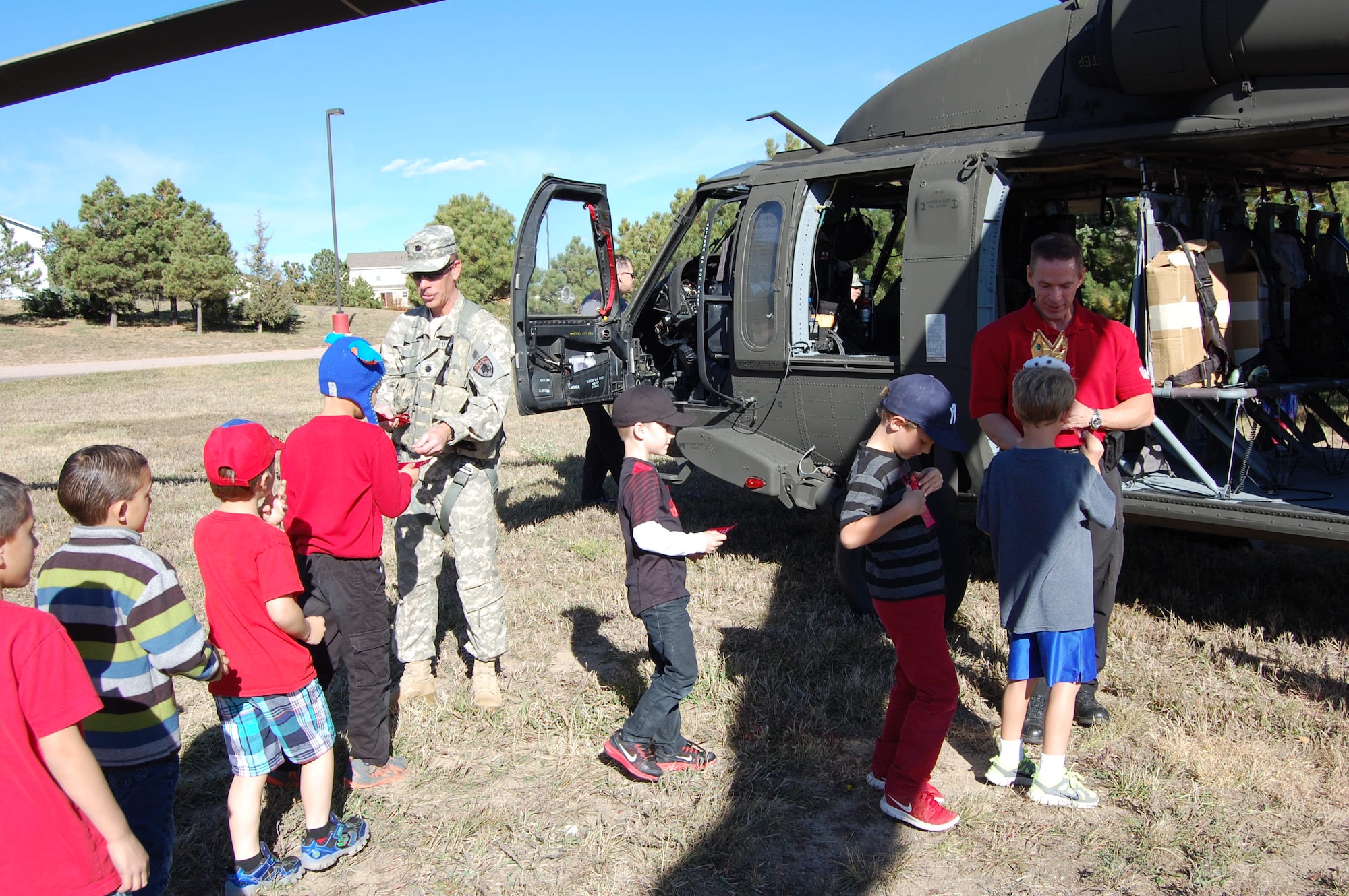 Lieutenant Col. Robert Soper, commander of the Colorado Joint Counterdrug Task Force and helicopter pilot, and Agent Albert Villasuso, Drug Enforcement Agency, pass out red ribbons to students at Ray Kilmer Elementary School, Colorado Springs, Colo. during their Red Ribbon Week October 21, 2014. Members of the CO-JCDTF and Drug Enforcement Agency flew into the schoolyard in a Colorado National Guard Blackhawk and talked to the children about making good choices to stay healthy and drug free. (U.S. Air National Guard photo by Capt. Kinder Blacke)