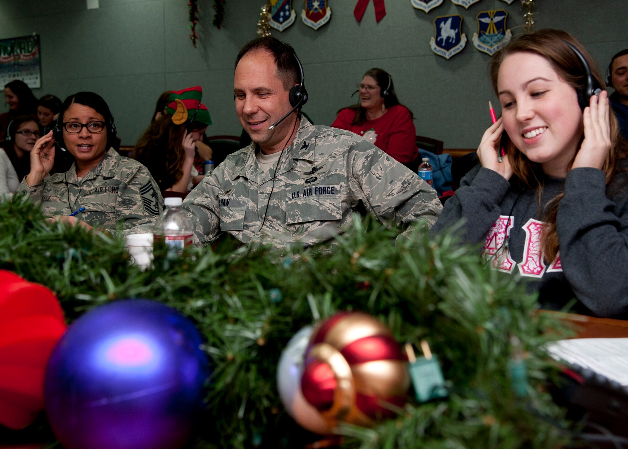 PETERSON AIR FORCE BASE, Colo. – Chief Master Sgt. Idalia A. Peele, 21st Space Wing command chief, Col. John E. Shaw, 21st SW commander, and Rachel Shaw, daughter of Col. Shaw, answer phone calls from families around the world for the annual NORAD Tracks Santa event, Dec. 24, 2014. Started by a wrong phone number in a Sears flyer, this is the 59th year for the event where volunteers will answer phone calls and emails from children from all over the world asking where Santa Claus is on his route. NORAD also provides a website showing where Santa is, where he is going to next and how many gifts he has delivered. For more information on the event, go to www.noradsanta.org. (U.S. Air Force photo by Senior Airman Tiffany DeNault)