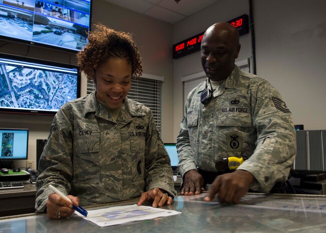 Staff Sgt. Jessica Clay, 628th Security Forces Squadron Base Defense Operations Center controller, and Tech. Sgt. Dwayne Hurt, 628th SFS swings  flight chief, review the patrolmen schedule Dec. 30, 2014, at the Base Defense Operations Center at Joint Base Charleston, S.C. The 628th SFS defends all assets and personnel on JB Charleston, even during the holiday season when many Airmen and Sailors are taking time off. During the holidays, SFS forces switch to 12-hour shifts instead of their usual eight, and divide their duties into two elements to allow their personnel time off for the holidays. One element works the week of Christmas and the other element works the week of New Years. (U.S. Air Force photo/Senior Airman Jared Trimarchi) 