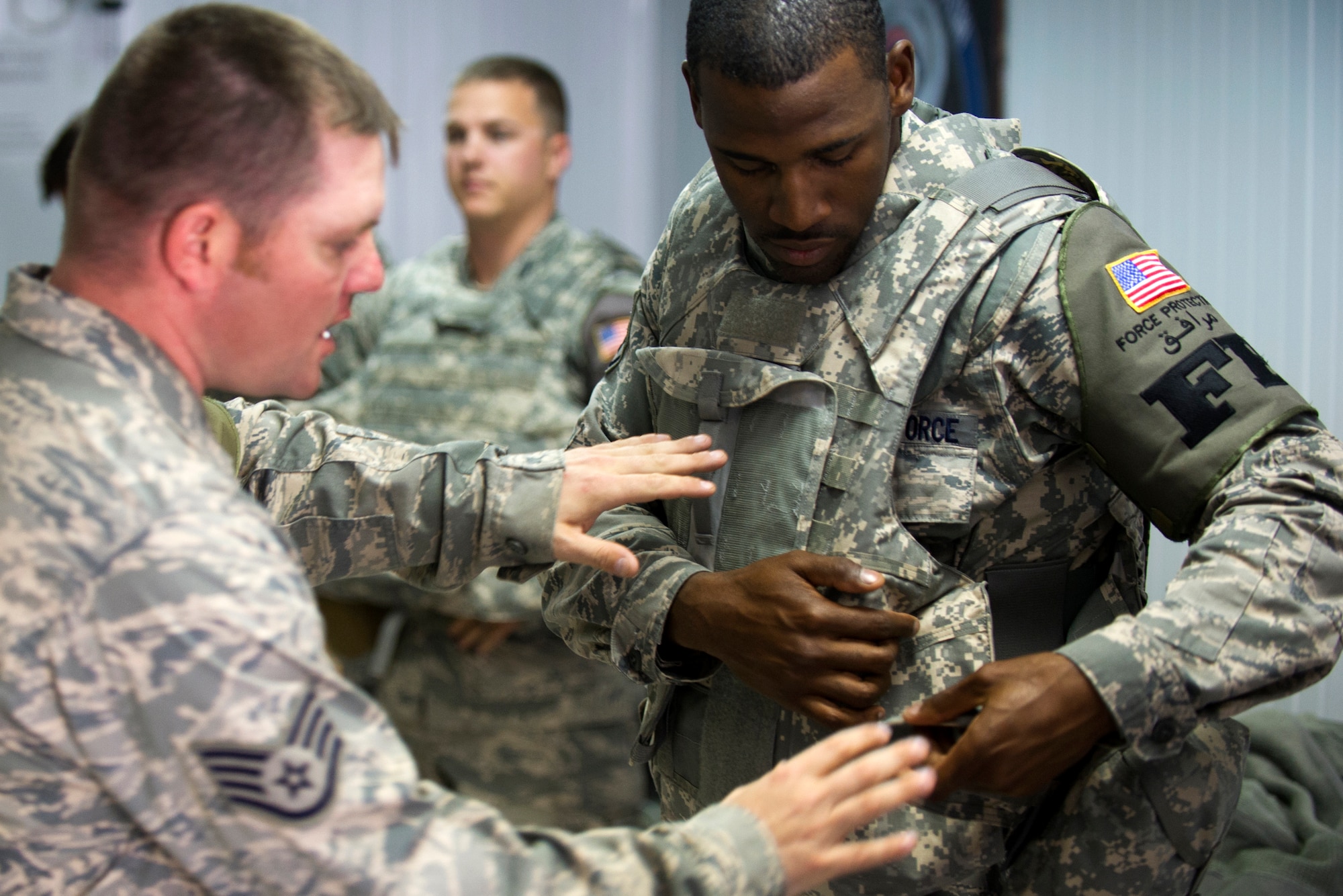 Staff Sgt. Matthew Parulis, 386th Expeditionary Security Forces Squadron, instructs Staff Sgt. Andre Williams on the proper setup of his individual protective equipment.  Force Protection has partnered with Security Forces Defenders as part of a program designed to provide enhanced training opportunities on base defense for FP Airmen.  Williams is part of Force Protection assigned to the 386th Expeditionary Civil Engineer Squadron. (U.S. Air Force photo by Senior Master Sgt. Burke Baker) 