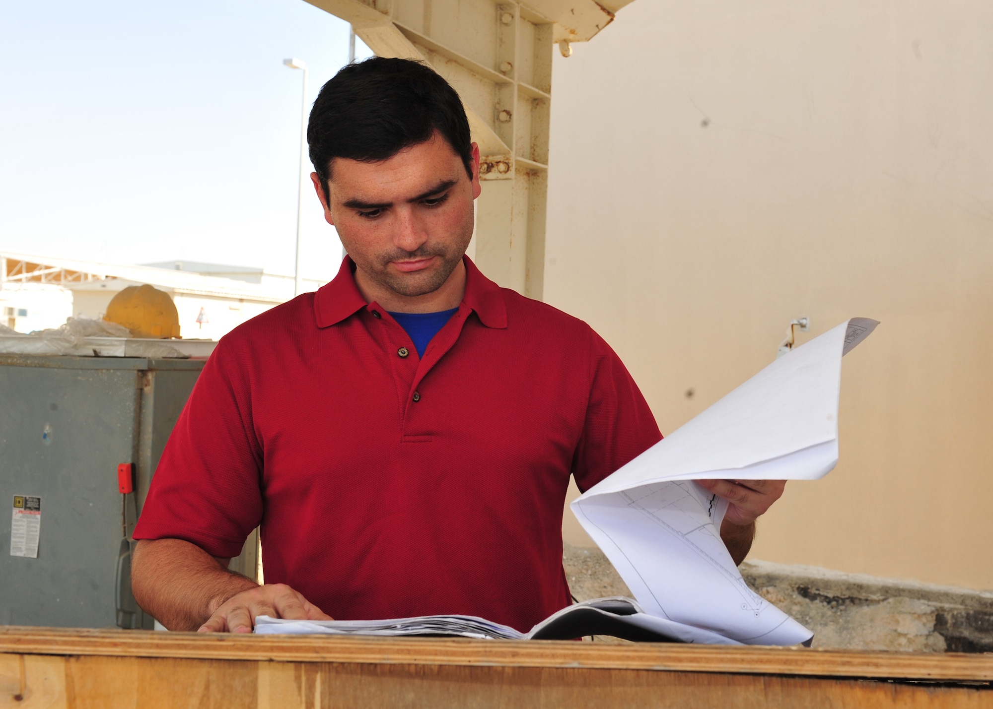 Timothy Lohn, a contracting specialist assigned to the 380th Expeditionary Contracting Squadron, reviews building plans at a construction site here, Jan. 29, 2014. Lohn is responsible for overseeing the construction contracts on base. (U.S. Air Force photo/Staff Sgt. Michael Means)